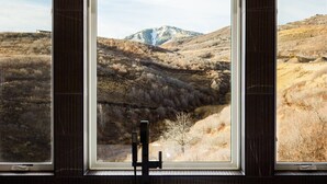 Ein Badezimmer mit einem großen Fenster und Blick auf eine gebirgige Landschaft.