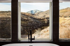 Ein Badezimmer mit einem großen Fenster und Blick auf eine gebirgige Landschaft.
