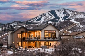 A two-story house with a balcony, large windows, and a view of a snowy mountain. - Luxury Ski Estate | Free Shuttle | Jordanelle Views (Heber City)