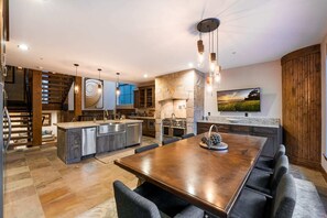 A modern kitchen with a large island, built-in appliances, and a dining area with a wooden table and chairs. - Experience luxury in this 3BR, 3.5BA loft in Deer Valley, Park City, with stunning mountain views. (Park City)