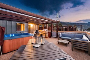 A deck with a hot tub, seating, and a view of the mountains. - Experience luxury in this 3BR, 3.5BA loft in Deer Valley, Park City, with stunning mountain views. (Park City)