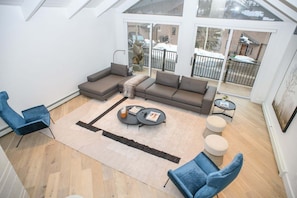 Ein modernes Wohnzimmer mit einer Eckcouch, einem Couchtisch und einer Glastür, die auf einen Balkon führt.