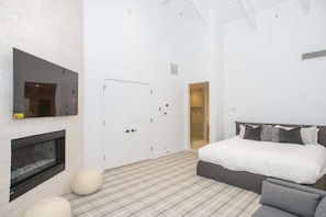 Ein Schlafzimmer mit Bett, Kamin, Kleiderschrank und Spiegel.