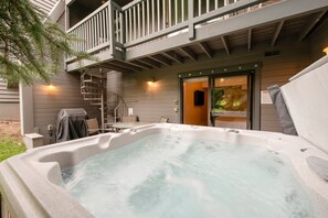 Ein Whirlpool mit Holzterrasse und einer Treppe, die zu einem Balkon führt.