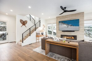 Ein modernes Wohnzimmer mit Kamin, einer Wendeltreppe und einem großen Fenster mit Blick auf Schnee.