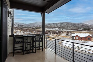 Ein Balkon mit Blick auf eine verschneite Landschaft, einem Tisch und zwei Stühlen.