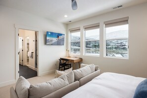 Ein Schlafzimmer mit einem Bett, einem Schreibtisch, einem Sessel, einem Sofa und einem Gemälde.