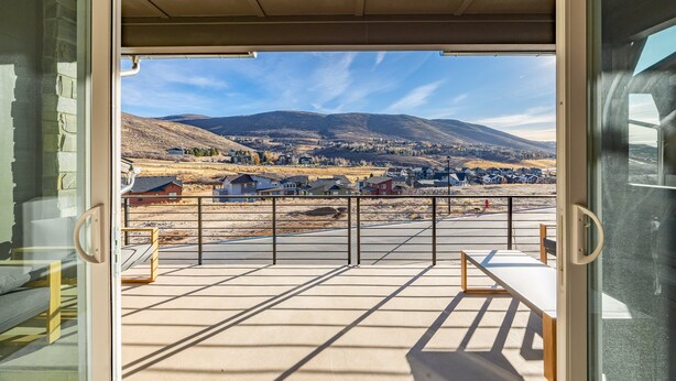 Eine geöffnete Tür zu einem Balkon mit Blick auf eine Stadt und Berge.