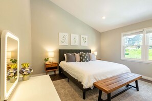 Ein Schlafzimmer mit Bett, Nachttischen, einer Bank, einem Spiegel und Wandbildern.
