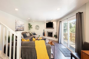 Ein modernes Wohnzimmer mit Kamin, einer Couch und einem Fernseher.
