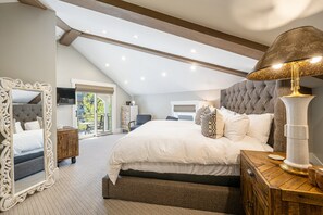 Ein geräumiges Schlafzimmer mit einem großen Bett, einem dekorativen Spiegel, einem hölzernen Nachttisch und einer modernen Lampe.