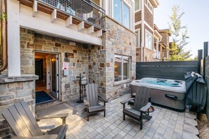 Ein Steinhaus mit Whirlpool, Sitzgelegenheiten im Freien und einer überdachten Terrasse.