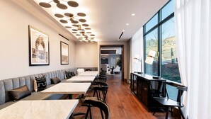 A modern dining area with a long bench, tables, and chairs, large windows with a view, and a ceiling with circular light fixtures. - 1BR in DV East, Steps to Gondola Ski-in/out, Amenities (Park City)