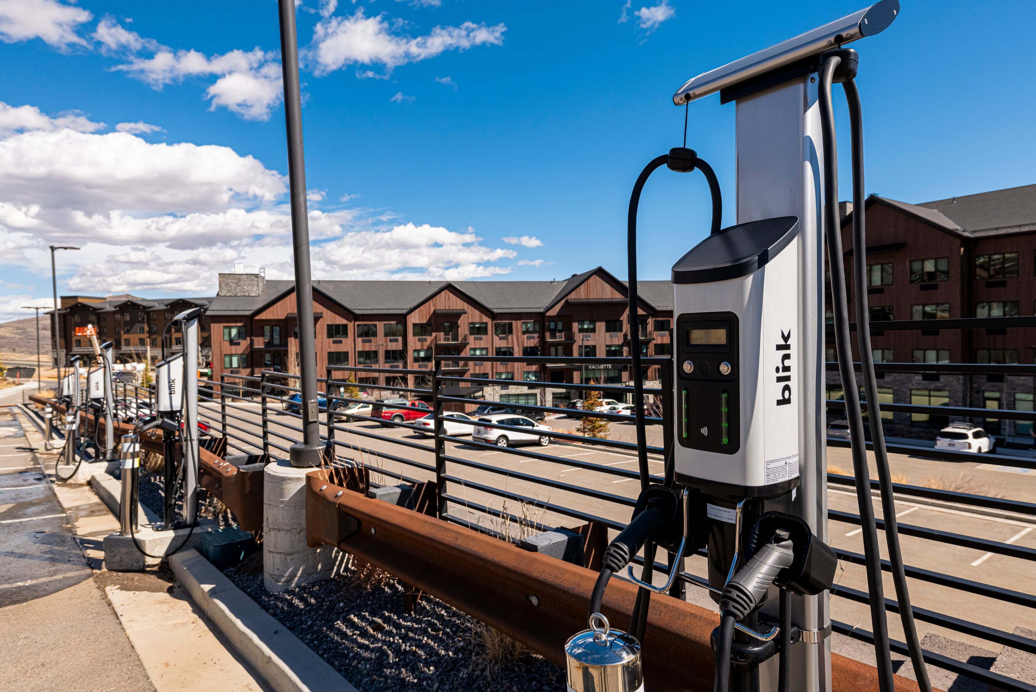 A row of electric vehicle charging stations with a view of a building in the background.