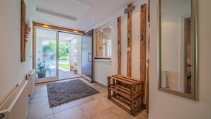 A hallway with a wooden bench, a large mirror, and a door leading to a garden. - Modern holiday apartment with terrace and garden (Mittersill)