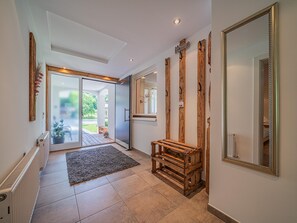 A hallway with a wooden bench, a large mirror, and a door leading to a garden.
