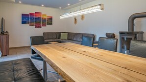 A modern living room with a wooden dining table, a grey sofa, and a fireplace. - Modern holiday apartment with terrace and garden (Mittersill)