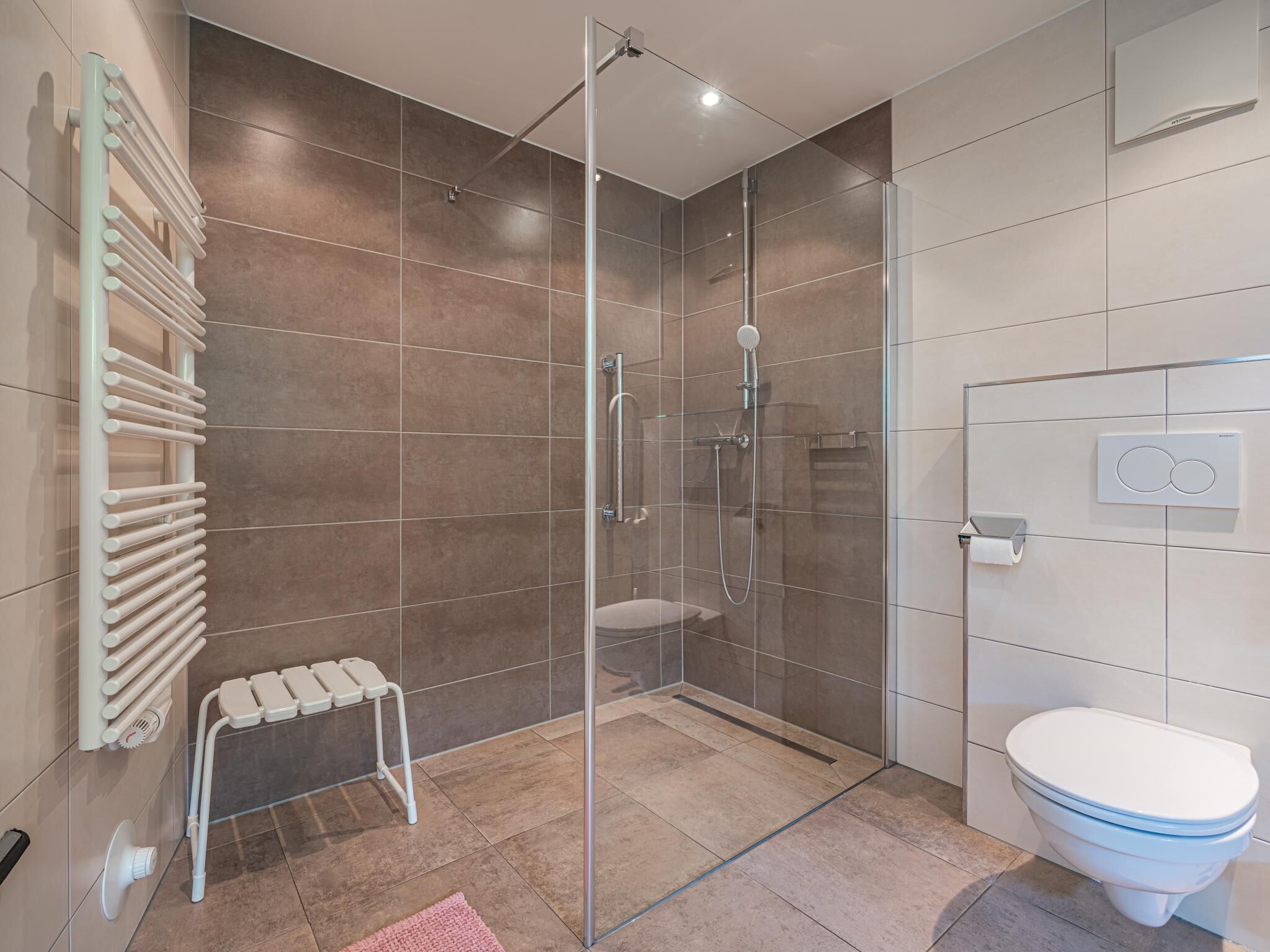 Ein modernes Badezimmer mit einer Duschkabine, einer weißen Toilette und einem Handtuchhalter.