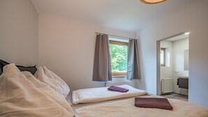 A bedroom with a bed, a window with curtains, a radiator, and a bathroom visible through an open door. - Modern holiday apartment with terrace and garden (Mittersill)