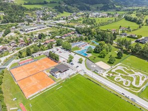 An aerial view of a sports complex with tennis courts, a swimming pool, and a golf course.