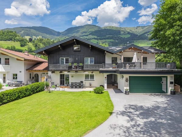 A two-story house with a balcony, a garage, and a well-maintained lawn.