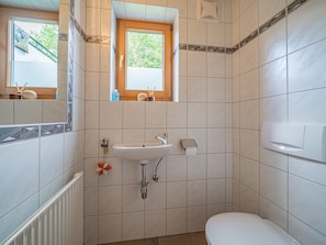Une salle de bain avec un lavabo, des toilettes et une fenêtre.
