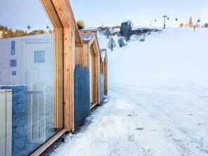 A snow-covered ski slope with wooden buildings and a ski lift in the background. - Apartment with sauna directly on the slope (Hinterglemm)