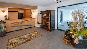 A reception area with a wooden counter, a vintage telephone, and a glass display case with shoes. - Ski-in apartment with sauna in the house (Hinterglemm)