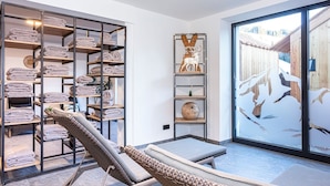 A spa room with a massage table, a towel rack, and a view of a wooden deck. - Ski-in apartment with sauna in the house (Hinterglemm)