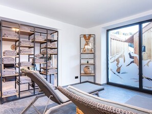 Ein Spa-Raum mit Massagetisch, Handtuchhalter und Blick auf eine Holzterrasse.