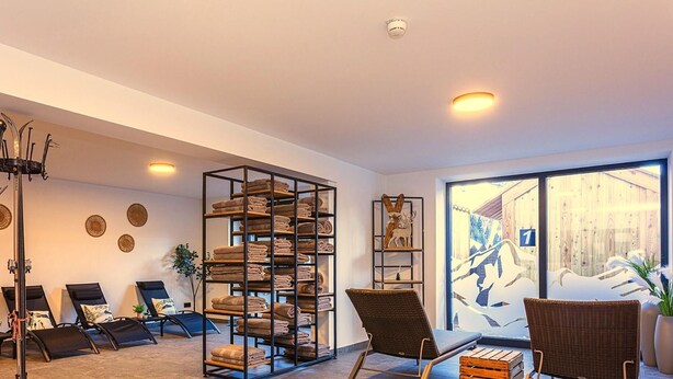 Ein modernes Interieur mit einem großen Fenster, einem Wandregal mit Handtüchern und zwei Korbstühlen.