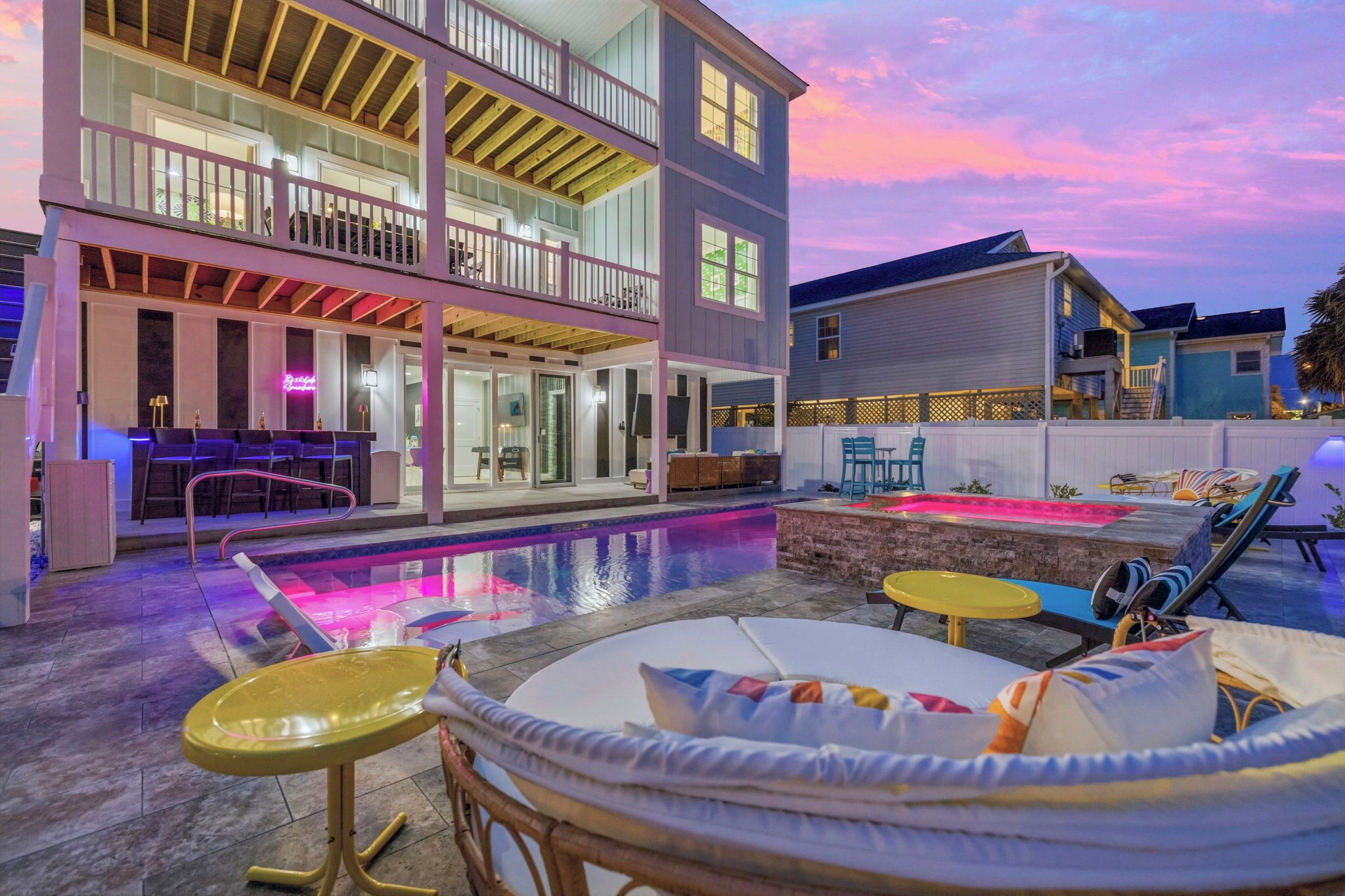 A two-story building with a pool area, outdoor seating, and a bar.