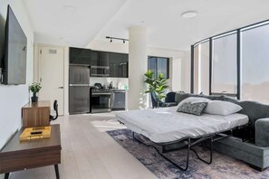 Ein modernes Apartment mit Küchenzeile, einem Bett, einer Couch und einem Essbereich.