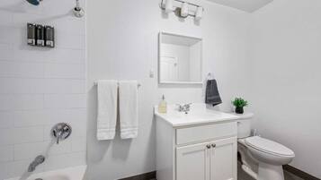 Ein modernes Badezimmer mit Waschbecken, Spiegel und Toilette, sowie einer Dusche mit Duschbrause.
