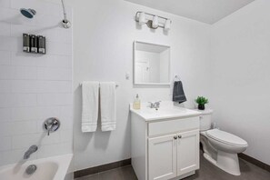 Ein modernes Badezimmer mit Waschbecken, Spiegel und Toilette, sowie einer Dusche mit Duschbrause.