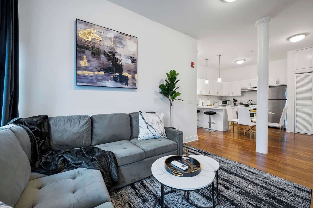 Ein modernes Wohnzimmer mit einem grauen Sofa, einem Couchtisch und einem Gemälde an der Wand.