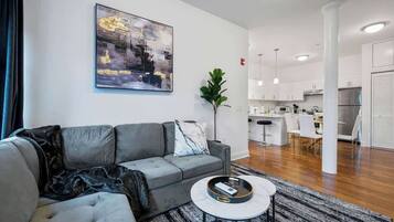 Ein modernes Wohnzimmer mit einem grauen Sofa, einem Couchtisch und einem Gemälde an der Wand.