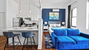 Eine moderne Wohnung mit Küche, Essbereich und Wohnzimmer mit blauem Sofa.