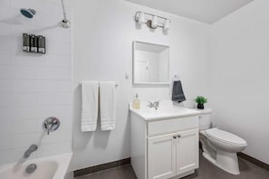 Ein modernes Badezimmer mit Waschbecken, Spiegel und Toilette, sowie einer Dusche mit Duschbrause.