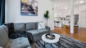 A modern living room with a grey sofa, a coffee table, and a painting on the wall. - 20 Min to MetLife Stadium • Perfect for FIFA Fans (Newark)