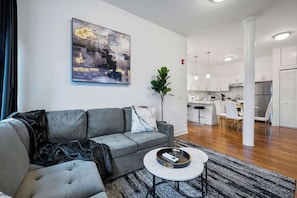 Ein modernes Wohnzimmer mit einem grauen Sofa, einem Couchtisch und einem Gemälde an der Wand.