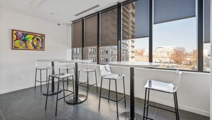A modern interior with a large window, a round table, and four bar stools. - Welcome to the 808 - Free parking - KING BED (East Orange)