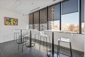 Ein moderner Raum mit einem großen Fenster, einem runden Tisch und vier Barhocker.