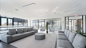 A modern lobby with a grey sectional sofa, a round coffee table, and a potted plant. - Welcome to the 808 - Free parking - KING BED (East Orange)