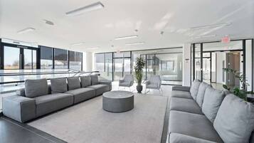 Eine moderne Lobby mit einem grauen Ecksofa, einem runden Couchtisch und einer Zimmerpflanze.