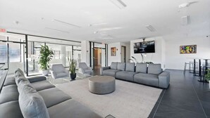 A modern lobby with a sofa, chairs, a round coffee table, and a TV mounted on the wall. - Welcome to the 808 - Free parking - KING BED (East Orange)