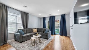 Ein modernes Wohnzimmer mit einem Ecksofa, einem runden Couchtisch und einem Flachbildfernseher.