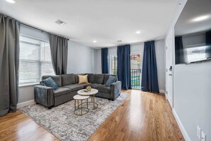 Ein modernes Wohnzimmer mit einem Ecksofa, einem runden Couchtisch und einem Flachbildfernseher.