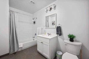 Ein modernes Badezimmer mit Badewanne, Toilette, Waschbecken und Spiegel.