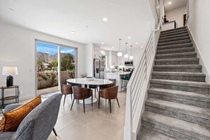 Eine moderne Küche mit Essbereich, einer Treppe und Blick ins Freie.